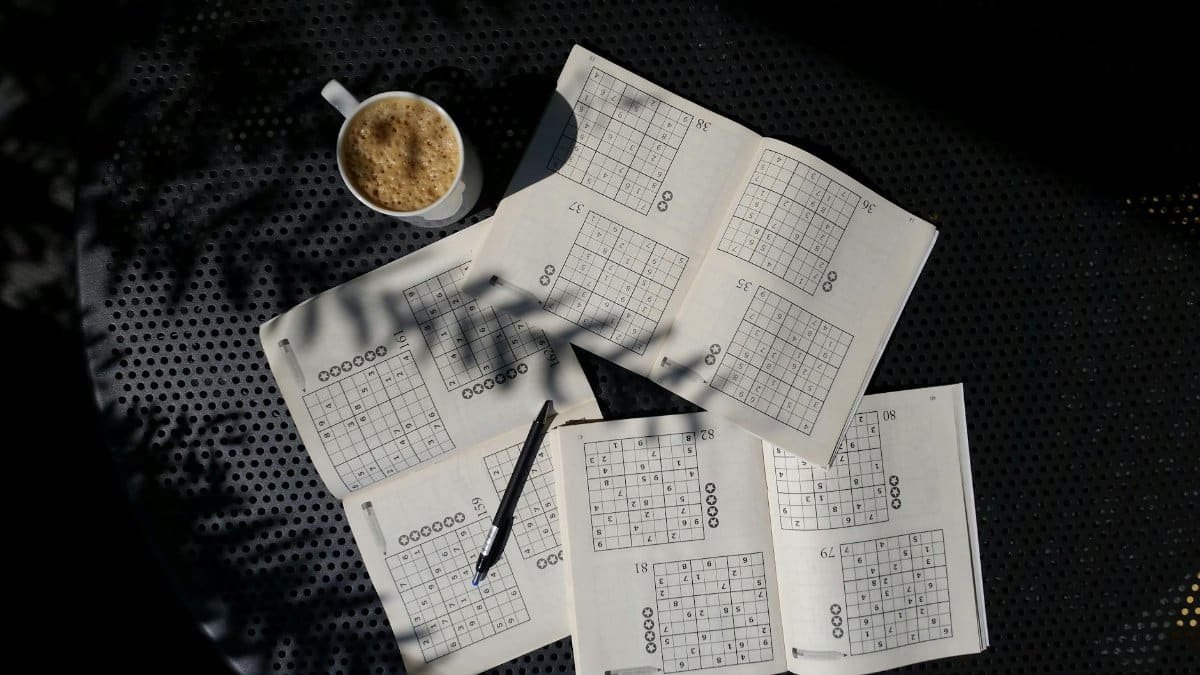 A calming flat lay of a Sudoku puzzle book with coffee, ideal for relaxation and focus.