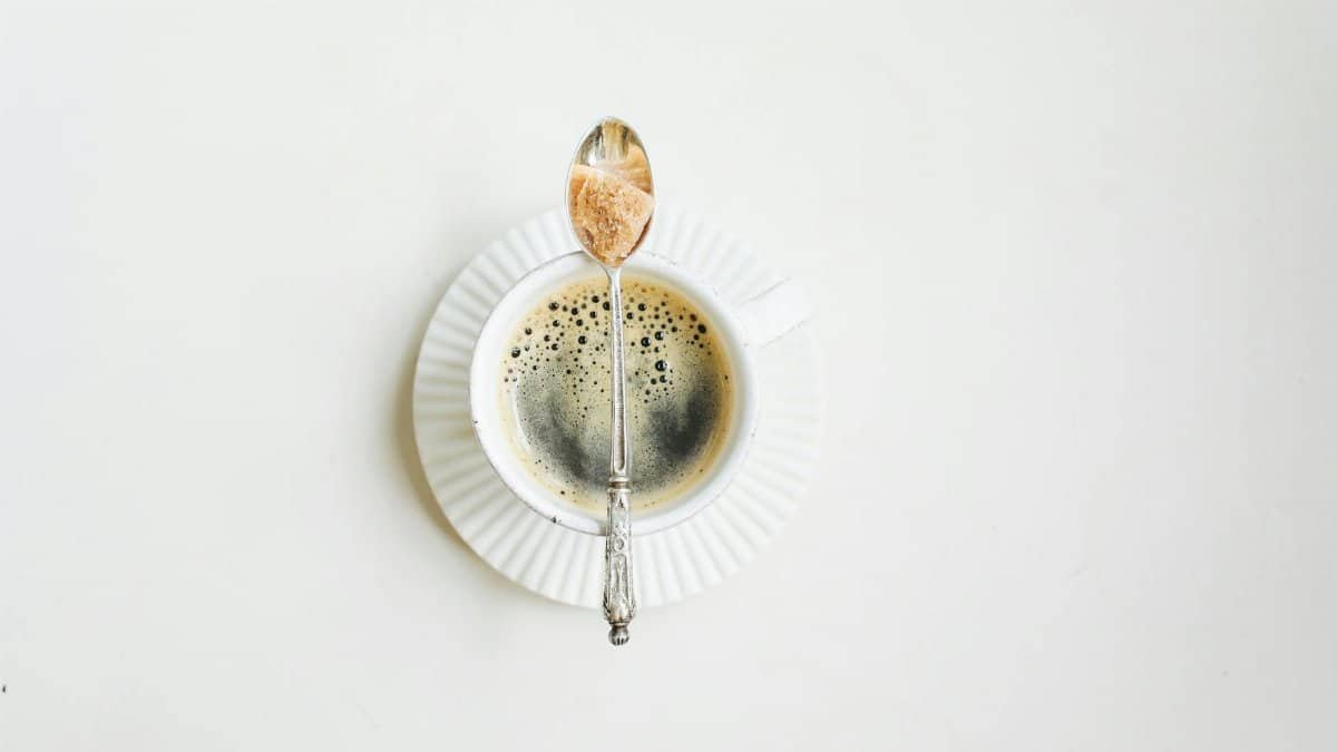 Elegant minimalist photo of a coffee cup with sugar spoon on a white background.