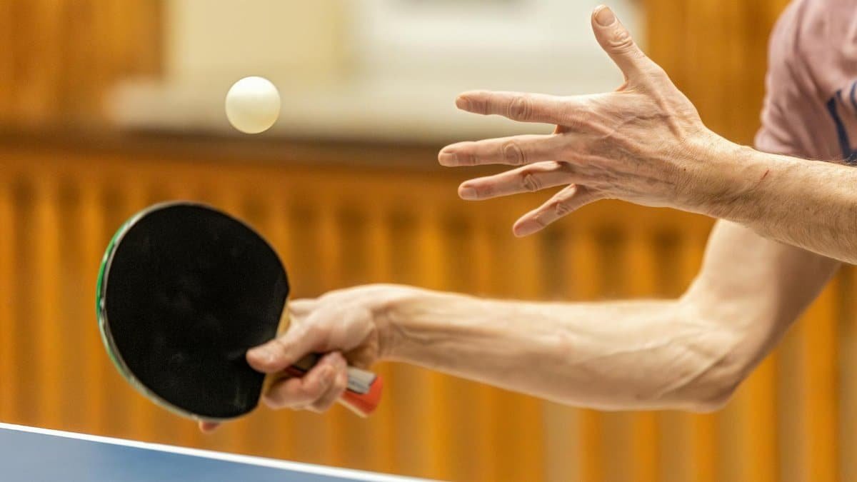 Dynamic close-up of table tennis player serving, capturing the motion and focus of the game.