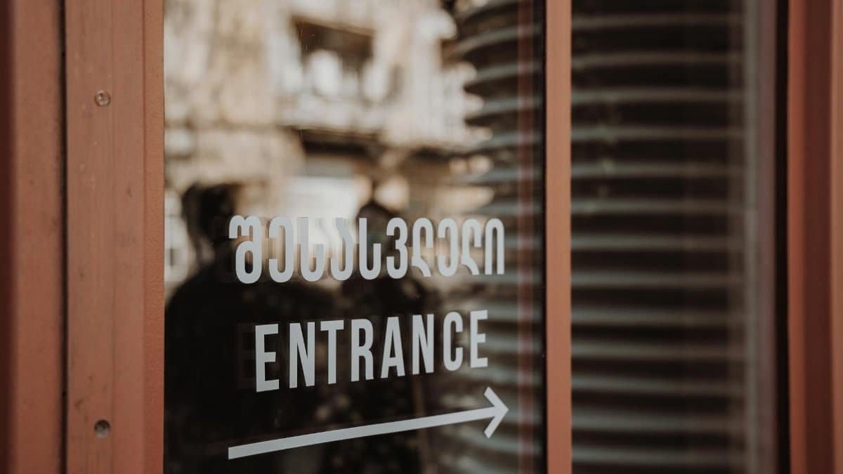 Close-up of a glass door with entrance text and urban reflections.