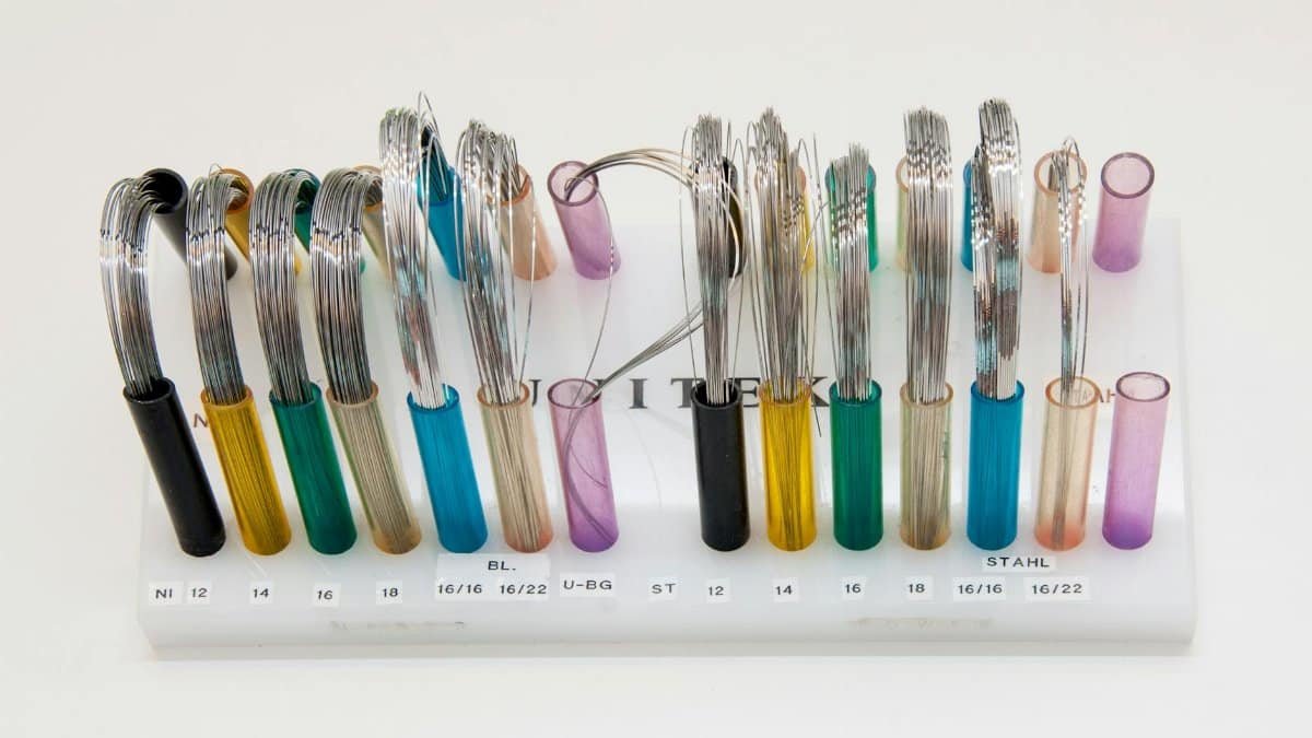 Display of colorful orthodontic wires arranged neatly on a stand.