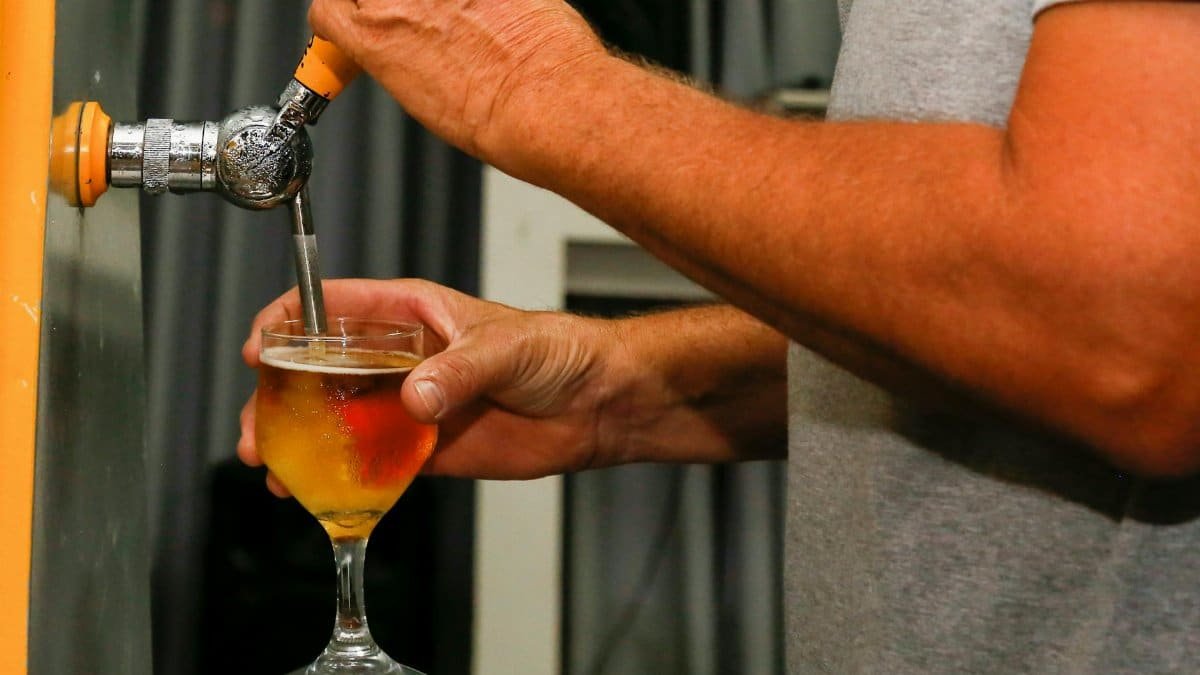 Close-up of a man's hands pouring a draft beer into a glass from a tap.