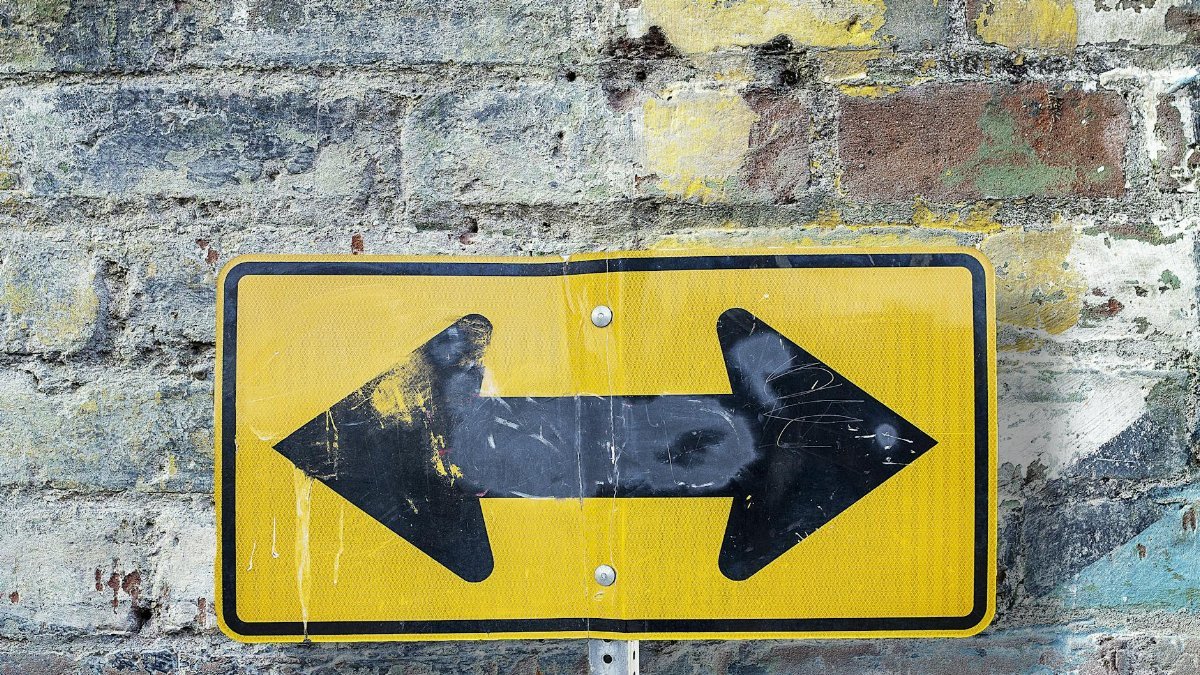 Weathered yellow two-way street sign on a textured rustic brick wall. Urban art style.