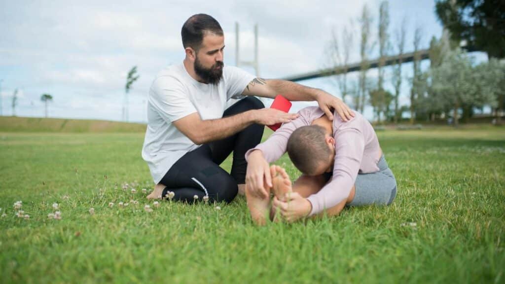 Two adults engaged in a stretching exercise in a park in Portugal.