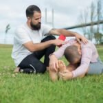 Two adults engaged in a stretching exercise in a park in Portugal.