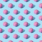 Creative composition of pink brain models in a repeating pattern on a light blue surface, showcasing abstract thinking.