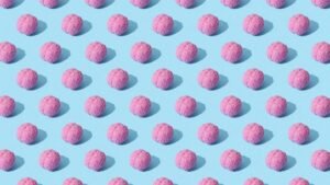 Creative composition of pink brain models in a repeating pattern on a light blue surface, showcasing abstract thinking.