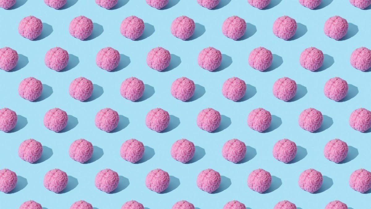 Creative composition of pink brain models in a repeating pattern on a light blue surface, showcasing abstract thinking.