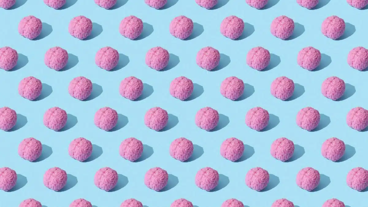 Creative composition of pink brain models in a repeating pattern on a light blue surface, showcasing abstract thinking.