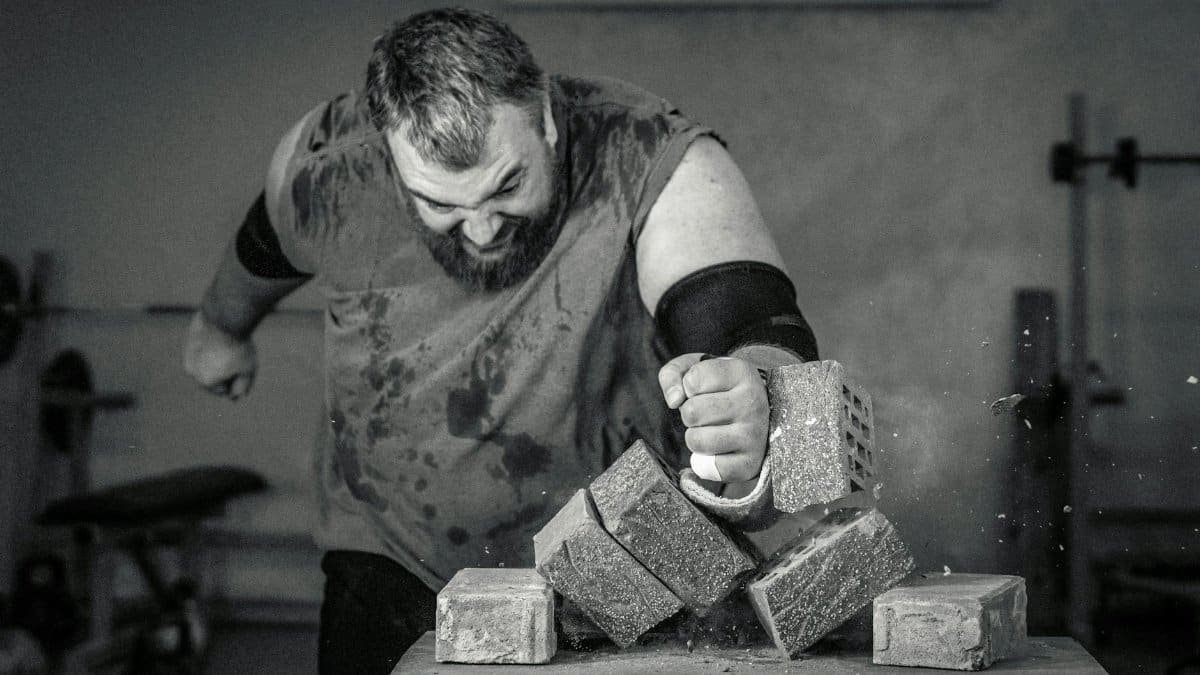 A powerful image of a strongman smashing concrete blocks with his fist, showcasing strength and determination.