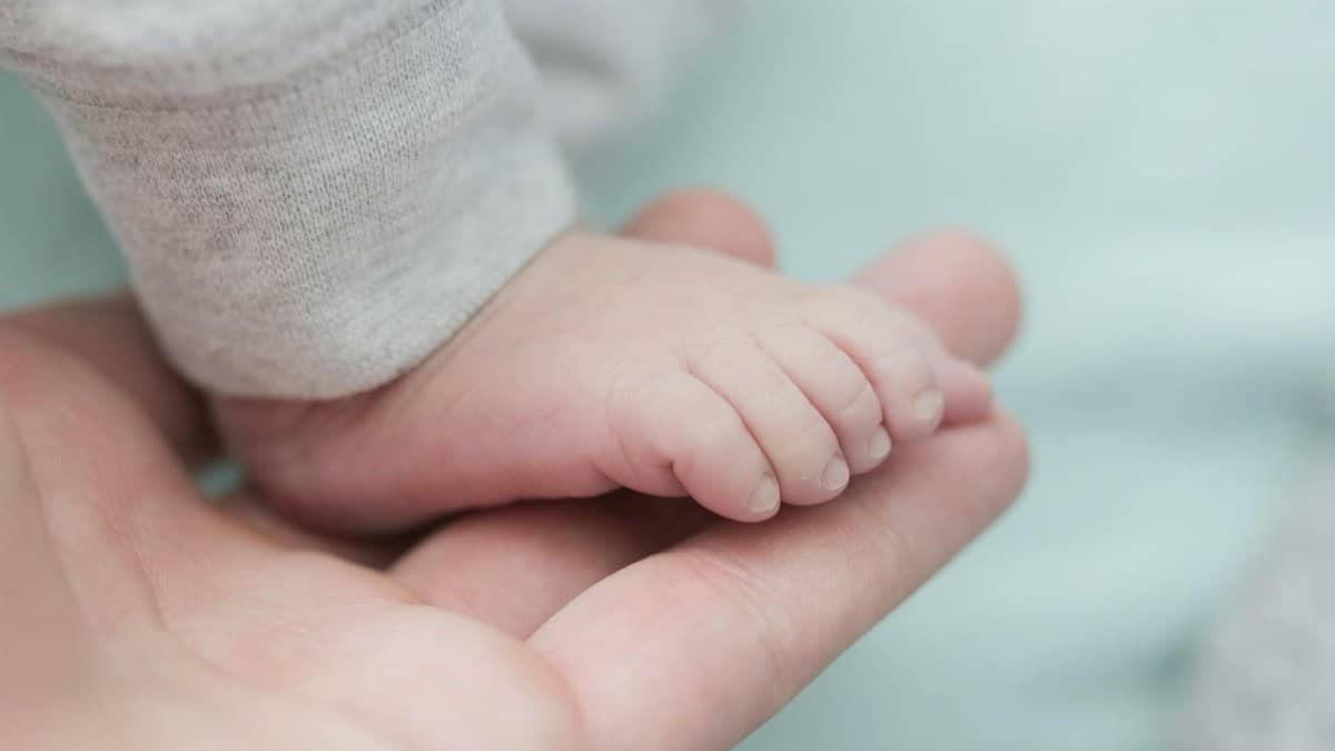Tender moment capturing a newborn's tiny foot held by a gentle hand.