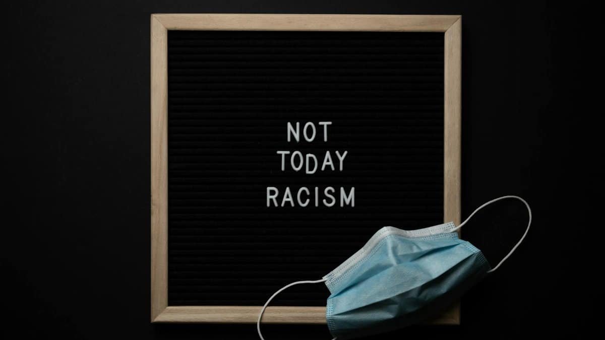 Blackboard with 'Not Today Racism' message and a surgical mask, symbolic of activism during the pandemic.