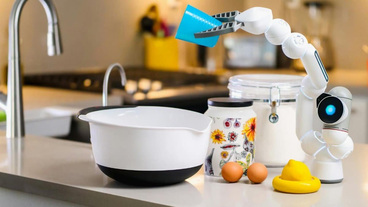 A robotic arm assists with mixing ingredients in a modern kitchen, showcasing advanced home technology.
