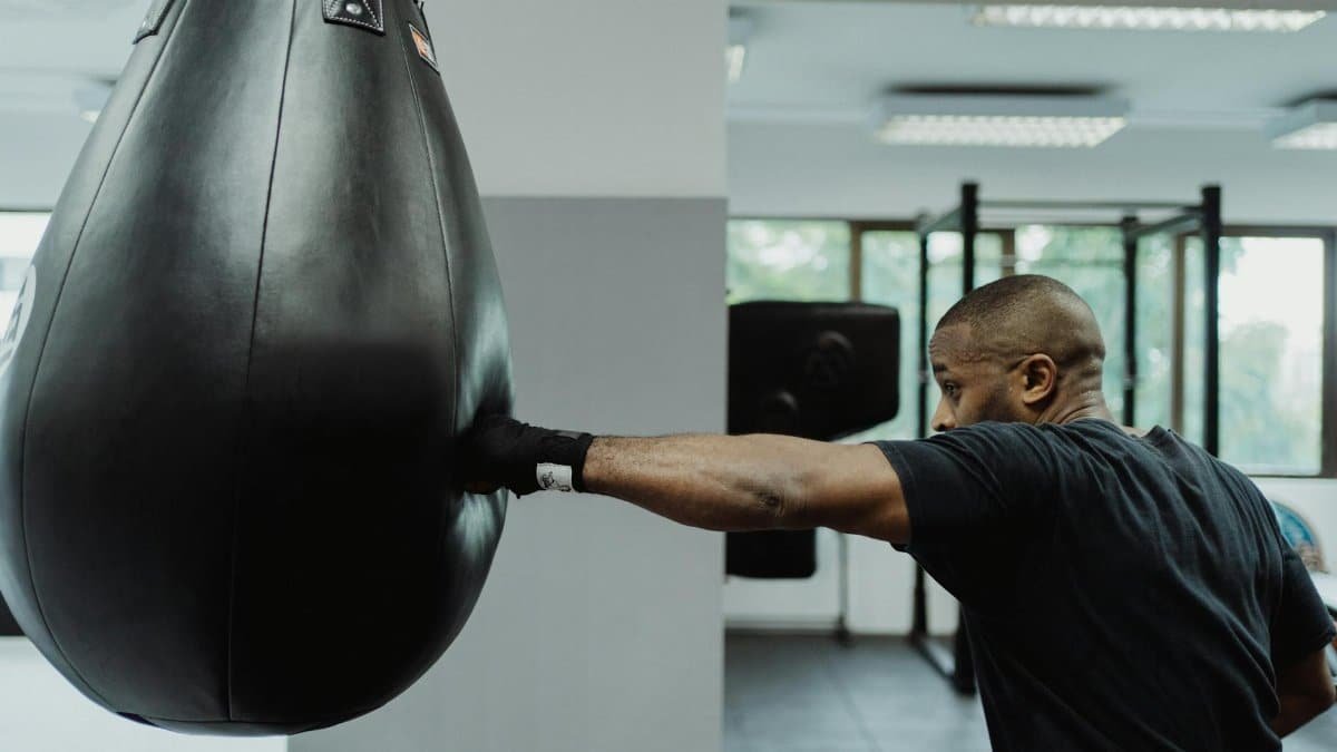 Boxer practicing punches on a punching bag in a gym setting.
