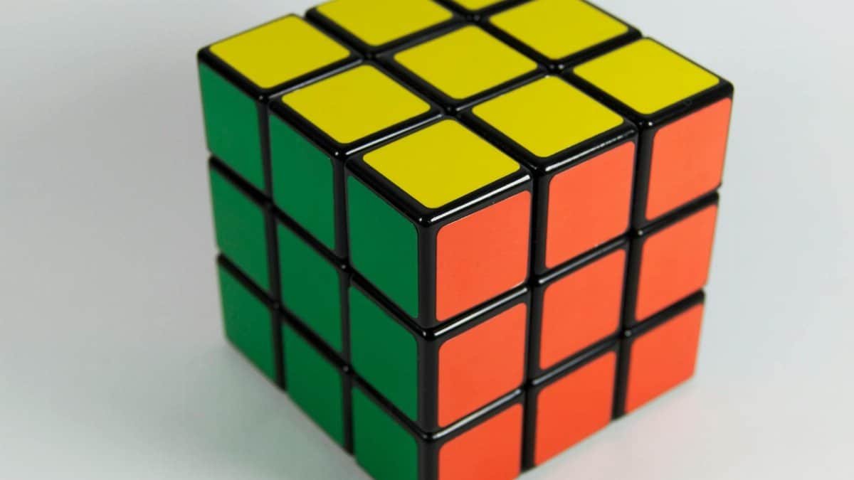 A solved Rubik's Cube displaying red, yellow, and green colors on a white backdrop. Perfect for puzzle enthusiasts.