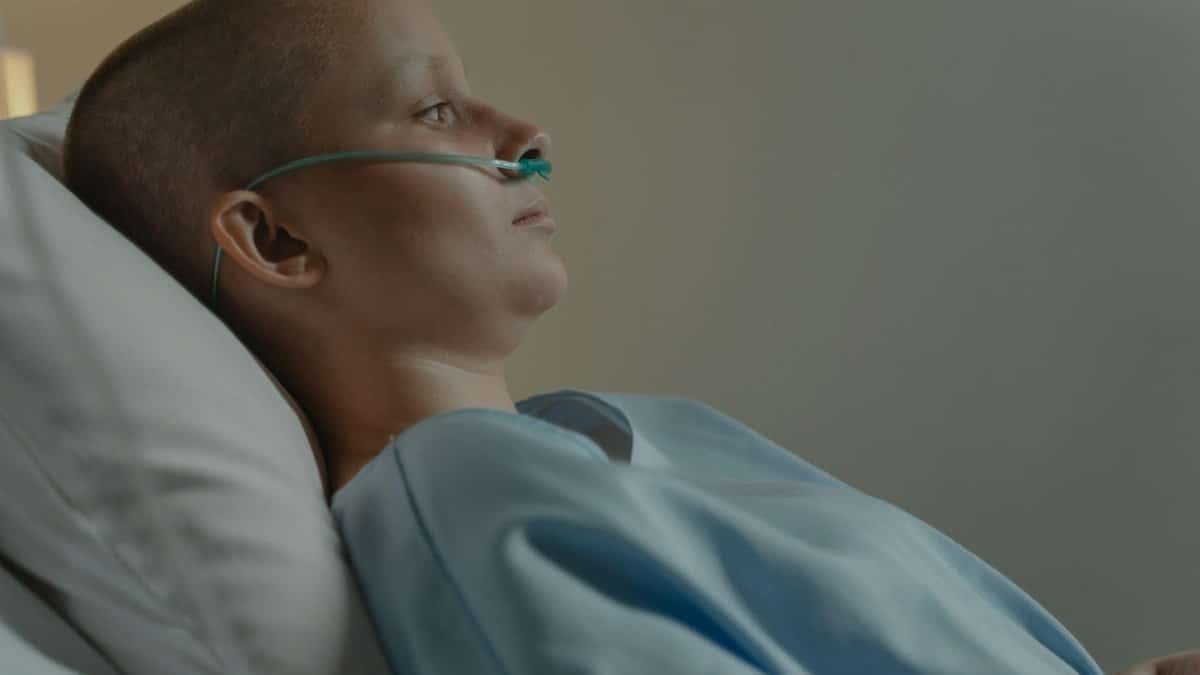 A woman in a hospital bed with a nasal cannula, reflecting health challenges.