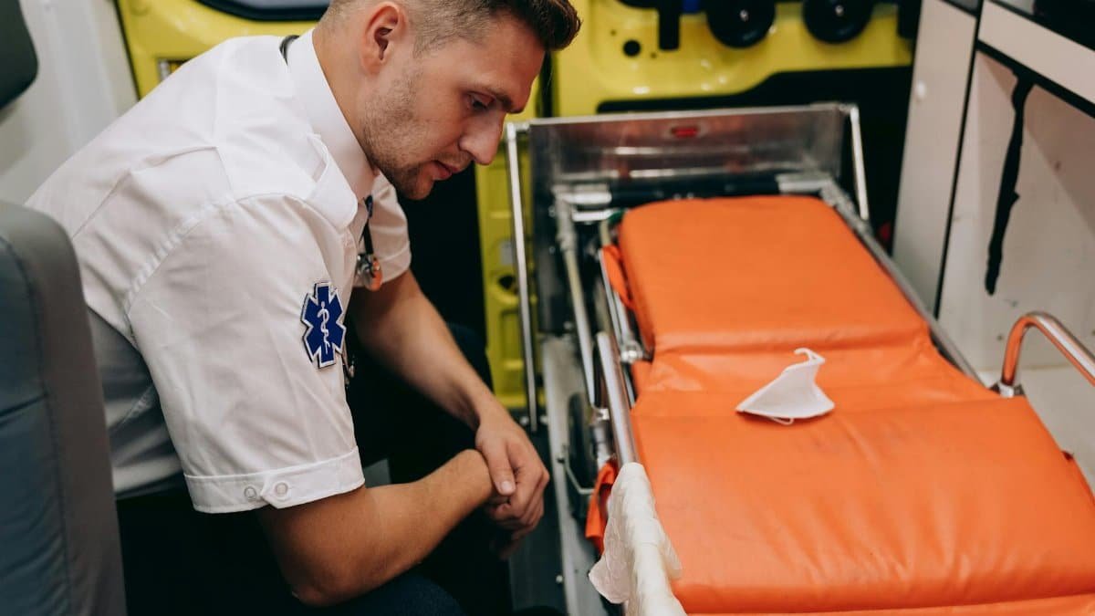 A paramedic prepares a stretcher inside an ambulance, focusing on readiness and professionalism.