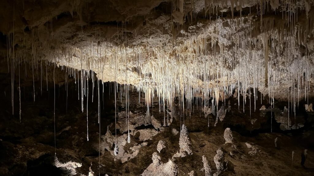 Dramatic view of stalactites hanging from a cave ceiling, casting shadows.
