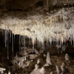 Dramatic view of stalactites hanging from a cave ceiling, casting shadows.