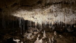 Dramatic view of stalactites hanging from a cave ceiling, casting shadows.