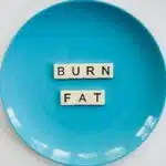 A conceptual image featuring the words 'Burn Fat' on a blue plate, symbolizing weight loss.