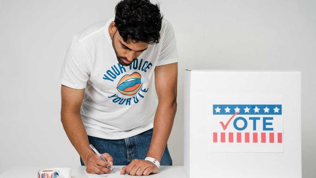 Man filling out ballot at polling station with a focus on civic duty and electoral participation.