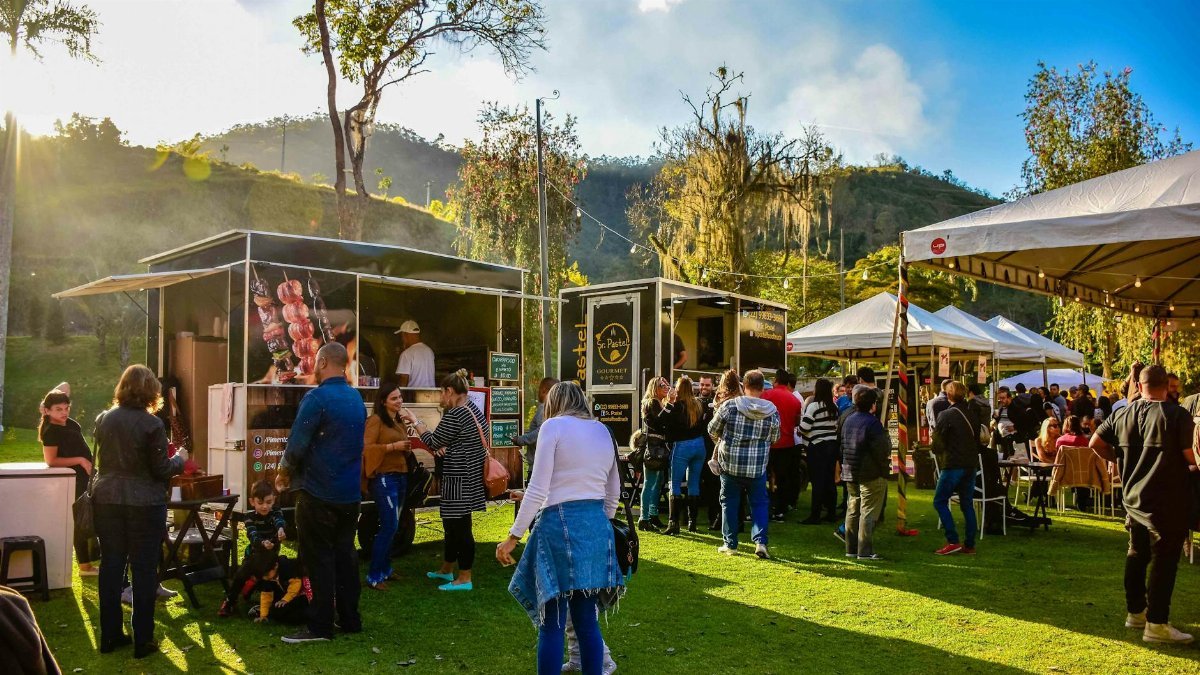 Lively outdoor street food market in Petropolis, Brazil with diverse food carts and a lively crowd.