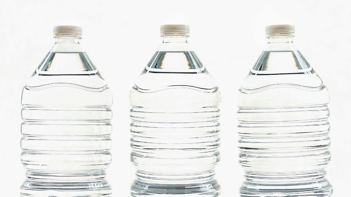 Three clear plastic bottles filled with water, standing side by side.