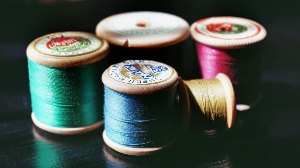 A collection of bright vintage sewing threads on wooden spools, perfect for crafting projects.