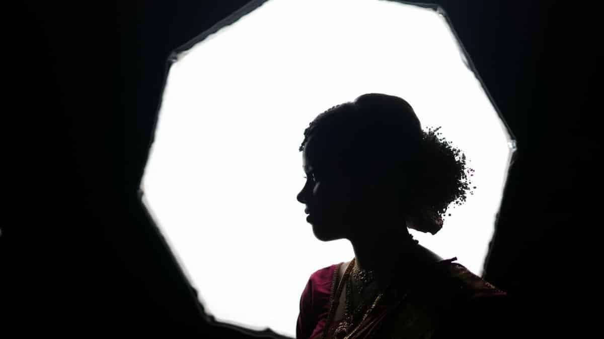 A dramatic silhouette of a woman in traditional attire against a bright softbox.