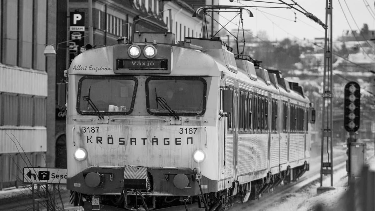 Black and white image of vintage train in snowy Jönköping, Sweden, creating a nostalgic winter scene.