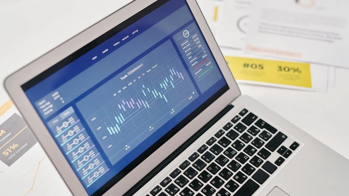 Open laptop displaying financial graphs and analytics with documents nearby, ideal for business presentations.