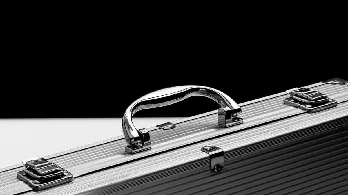 Close-up of a sturdy metal briefcase with a shiny chrome handle on a black and white background.