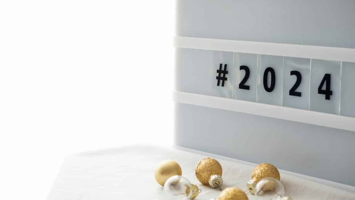 Elegant 2024 New Year setup with hashtag and gold baubles on white background.