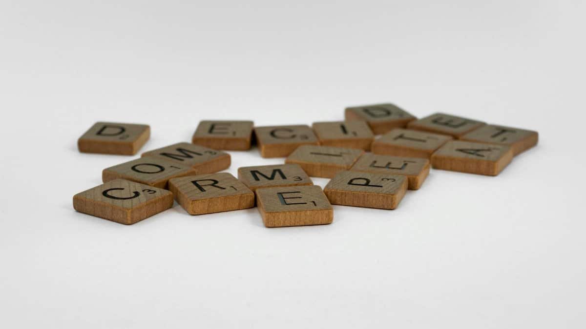 Close-up of wooden Scrabble tiles on a white surface, ideal for creative concepts.
