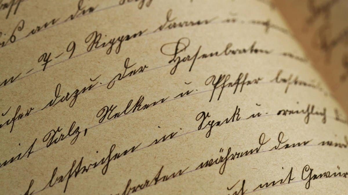 Close-up of vintage handwriting on antique aged paper with sepia tones.