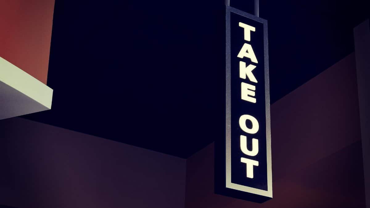 Vertical take out sign hanging indoors in a modern restaurant setting.