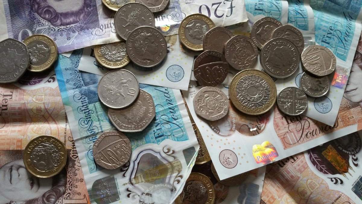 A close-up view of various British coins and banknotes, representing currency and finance.