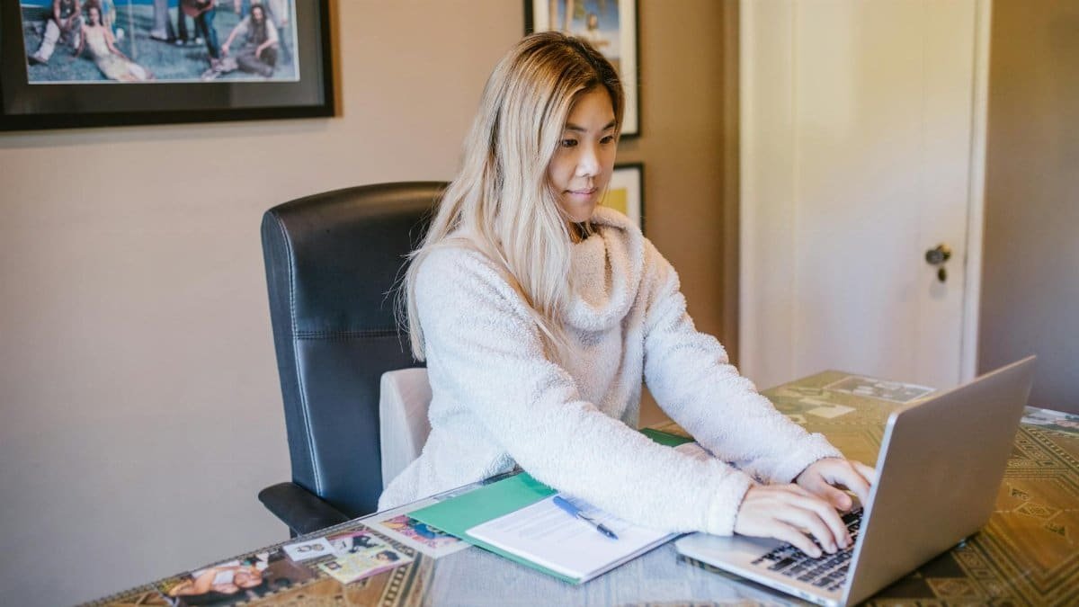 Young woman working remotely on laptop from home office, representing modern remote work lifestyle.