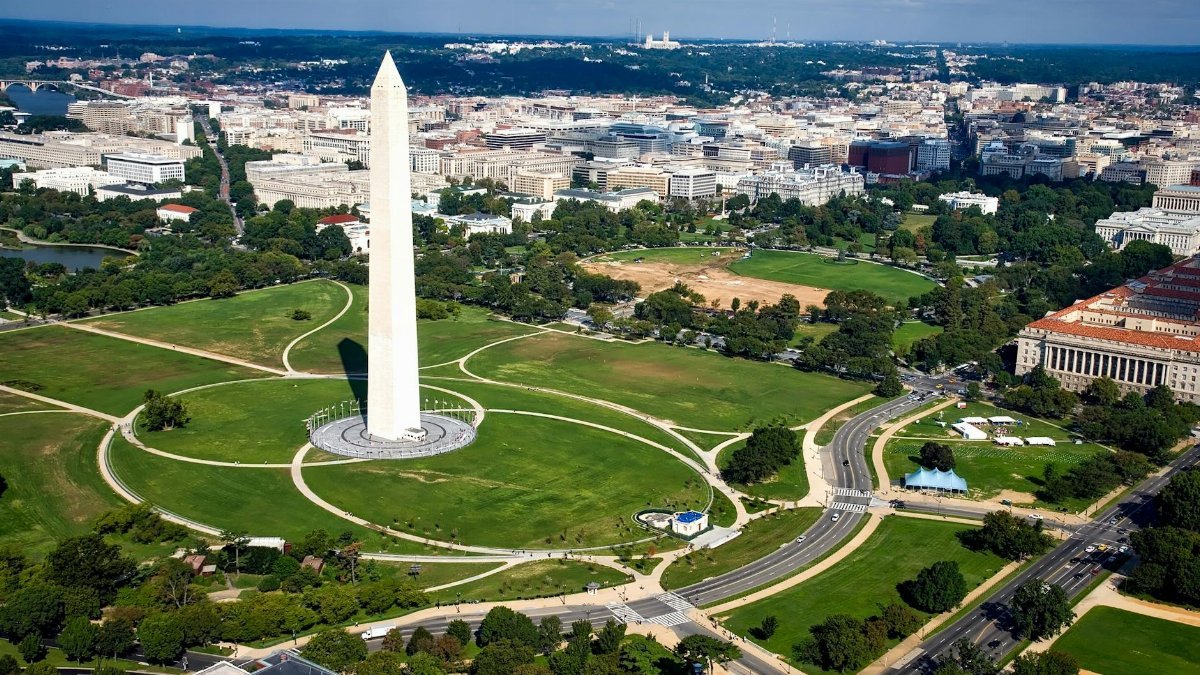 A breathtaking aerial view of the Washington Monument surrounded by cityscape and green landscapes.