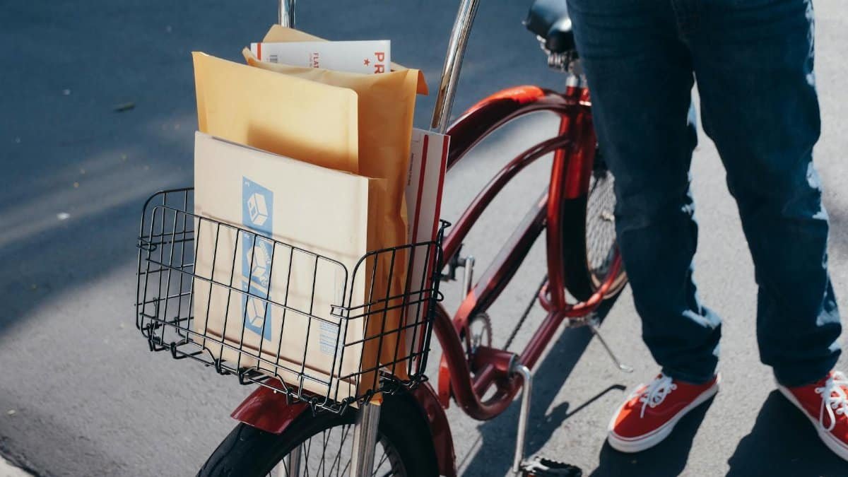 A bicycle with packages in the front basket on a sunny day, ready for delivery.