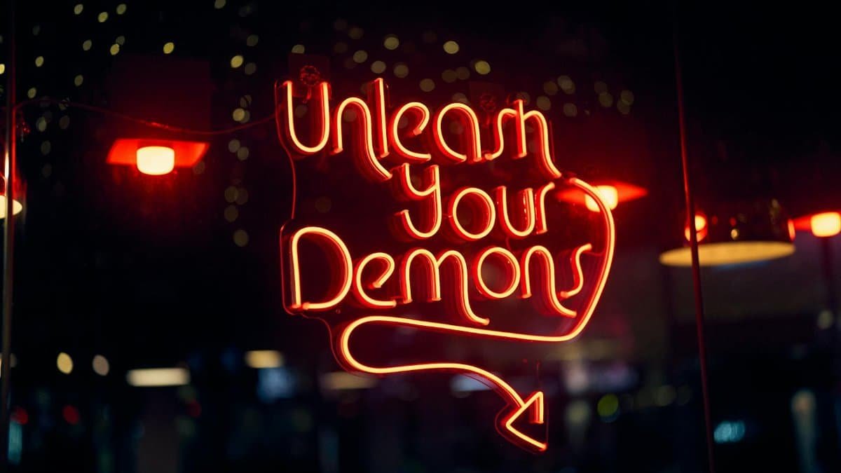 Vibrant neon sign 'Unleash Your Demons' glowing at night in Singapore.