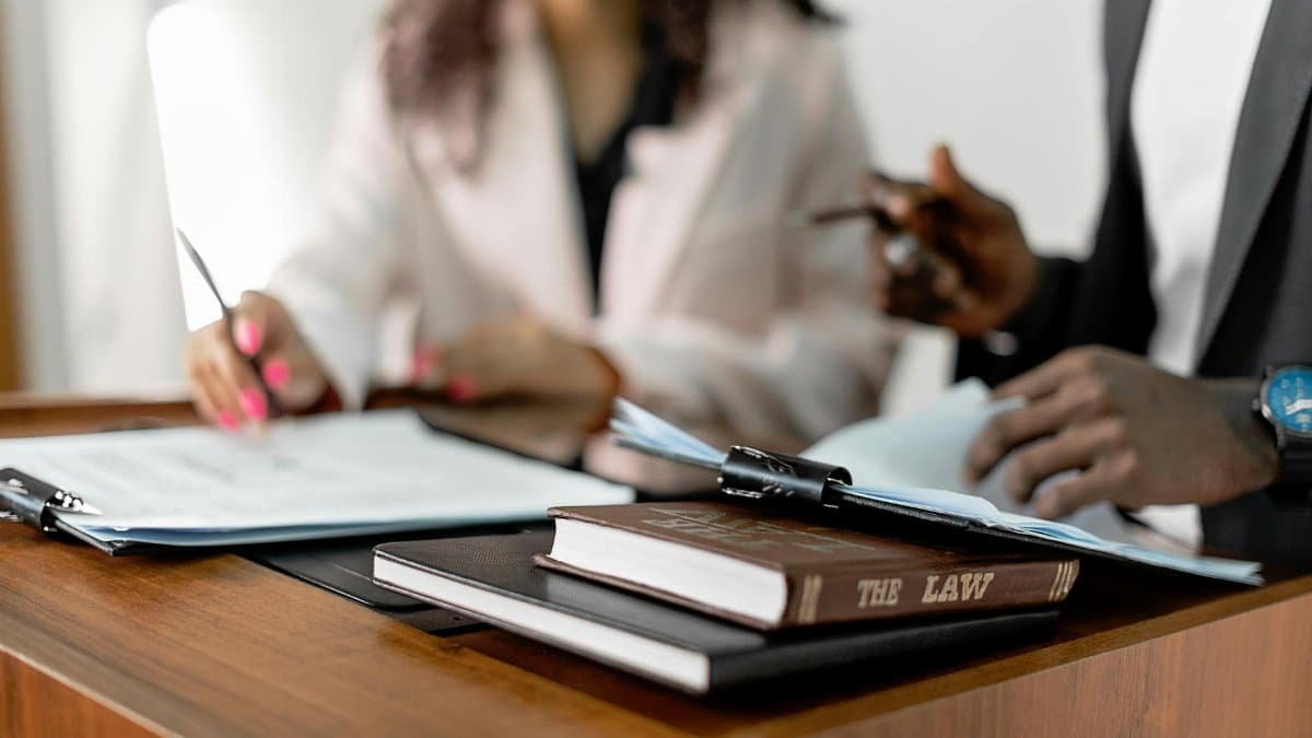 Two lawyers reviewing documents with law books on a desk. Professional legal environment.