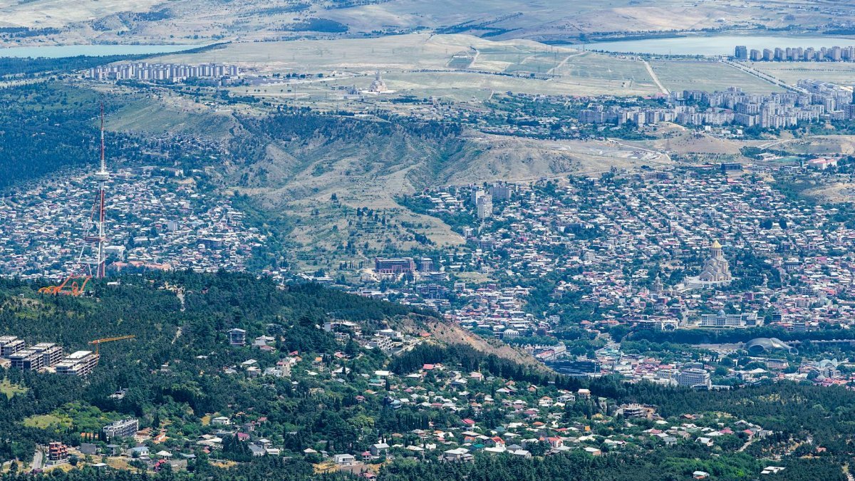 A breathtaking aerial view of Tbilisi, showcasing its urban landscape and surrounding hills in the summer.