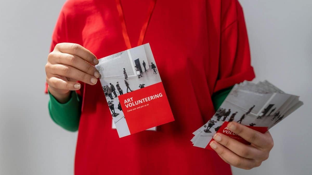 Close-up of a volunteer holding art volunteering flyers highlighting community service.