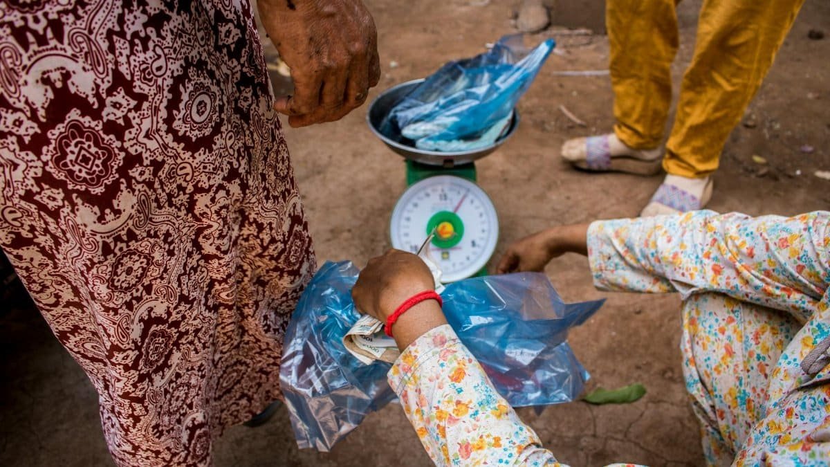 A vendor weighing goods at an outdoor market with traditional scales and colorful attire.