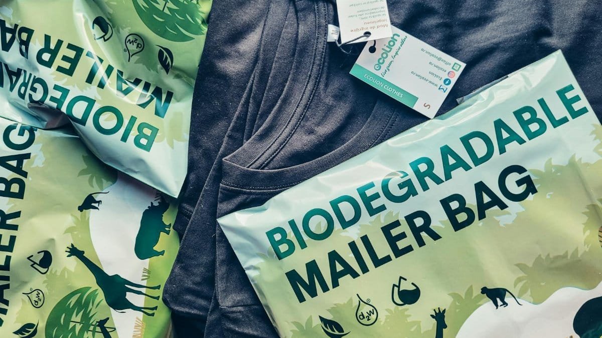 Close-up of biodegradable mailer bags and sustainable shirt promoting eco-friendly packaging.