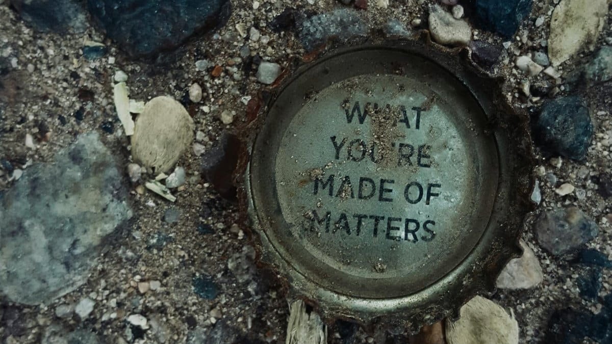 Photograph of a rusty bottle cap on gravel with the message 'What You're Made Of Matters.'