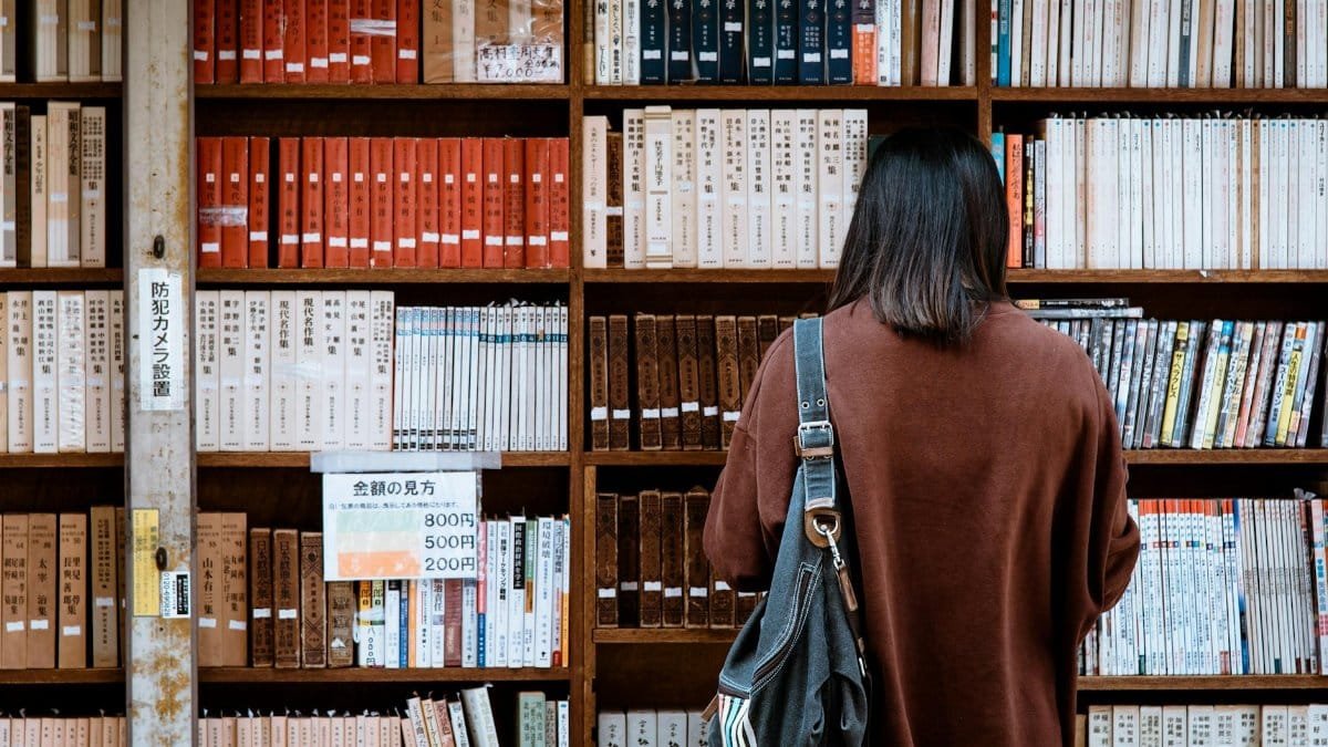Woman browsing books at a library in Nagano, Japan. Explore knowledge and literature.