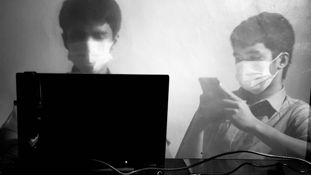 Double exposure of a masked man using a laptop and smartphone, depicting new normal workplace dynamics.